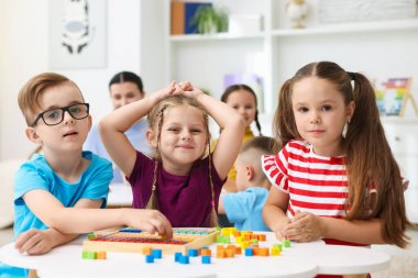 İlkokulda ders sırasında beyaz masalarda oturan sevimli çocuklar.