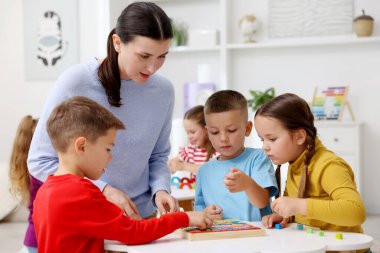 İlkokulda beyaz masadaki sevimli çocuklar ve öğretmenler.