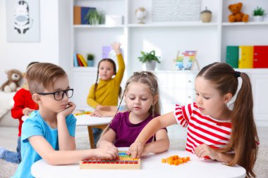 İlkokulda ders sırasında beyaz masalarda oturan sevimli çocuklar.