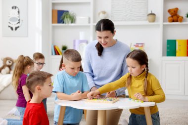 İlkokulda beyaz masadaki sevimli çocuklar ve öğretmenler.