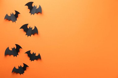 Cadılar Bayramı dekoru. Siyah kağıt yarasalar turuncu arka planda, düz yerde. Metin için boşluk