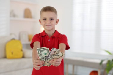 Evde cep harçlığı tutan küçük çocuk, seçici odaklı.