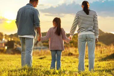 Aile gün batımında, arka planda el ele tutuşuyor.