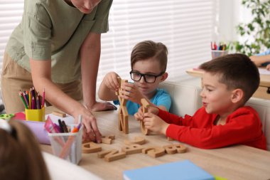 İlkokulda ahşap masada öğretmenden ders alan küçük çocuklar, yakın çekim.