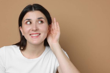 Gülümseyen kadın bej arka planda el ele hareketler gösteriyor. Metin için boşluk