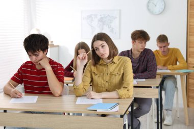 Ahşap masada sınava giren öğrenciler