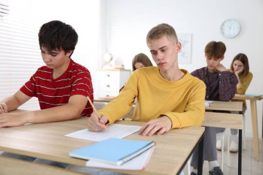 Ahşap masada sınava giren öğrenciler