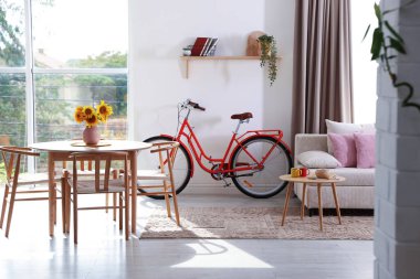 Odasında sandalye, kanepe ve bisiklet olan ahşap yemek masası.