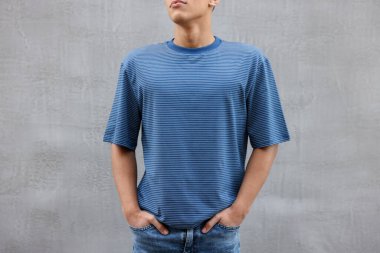 Gri duvarın yanında açık mavi tişört giyen genç adam, yakın plan. Tasarım için model