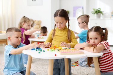 İlkokulda ders sırasında beyaz masalarda oturan sevimli çocuklar.