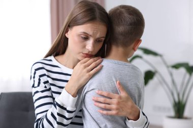 Anne, üzgün oğlunu evde destekleyip kucaklıyor.