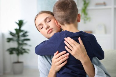 Anne, üzgün oğlunu evde destekleyip kucaklıyor.