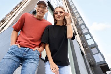 Genç bir kadın ve erkek açık havada boş tişörtler giyiyor, düşük açılı. Tasarım için model