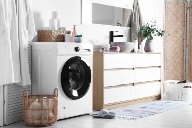 Çamaşır makinesi ve çamaşır sepeti banyoda lavabonun yanında. İç tasarım