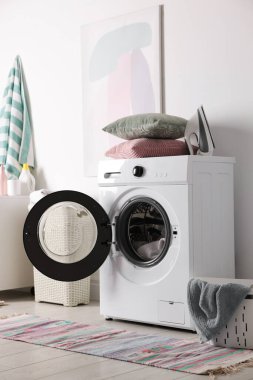 Çamaşır makinesi, sepeti ve deterjanı olan bir çamaşırhane.
