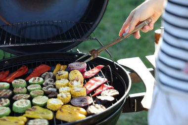 Vejetaryen barbeküsü. Dışarıdaki ızgarada sebze pişiren kadın, yakın plan.