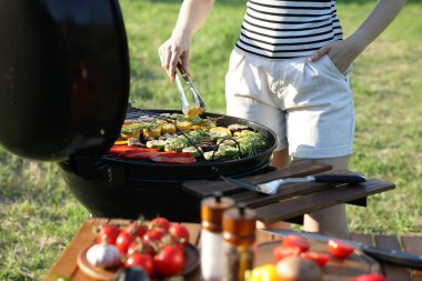 Vejetaryen barbeküsü. Dışarıdaki ızgarada sebze pişiren kadın, yakın plan.