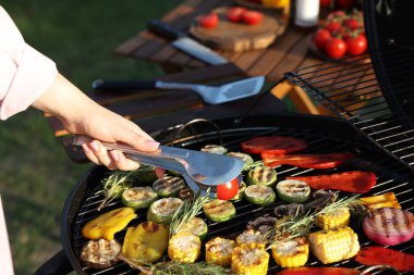 Vejetaryen barbeküsü. Dışarıdaki ızgarada sebze pişiren kadın, yakın plan.