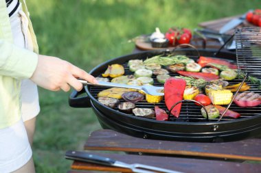 Vejetaryen barbeküsü. Dışarıdaki ızgarada sebze pişiren kadın, yakın plan.