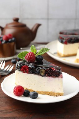 Bir parça lezzetli peynirli kek, böğürtlenli ve nane şekerli, ahşap masada servis ediliyor, yakın plan.