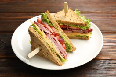 Delicious sandwiches with ham, cheese and vegetables on wooden table, closeup