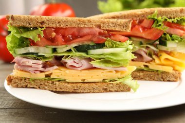Tasty sandwiches with ham, cheese and vegetables on wooden table, closeup