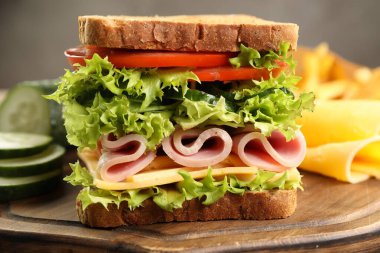 Tasty sandwich with ham, cheese and vegetables on table, closeup