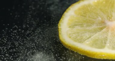 Koyu arkaplanda soda içinde limon dilimi, yakın plan.