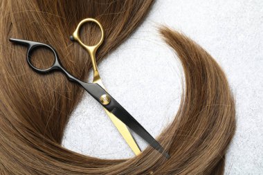 Açık arkaplanda güzel saç teli ve makas, üst manzara.