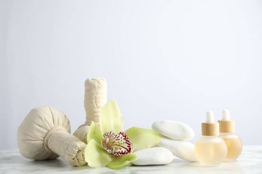Beyaz mermer sehpanın üzerinde hafif arka planda gerekli yağlar ve bitkisel poşetlerle güzel bir spa kompozisyonu.