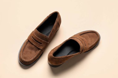 Bej arka planda bir çift şık deri ayakkabı, üst görünüm.