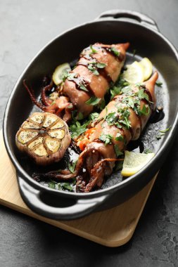 Siyah masada soslu ve sarımsaklı lezzetli kalamarlar, yakın plan.