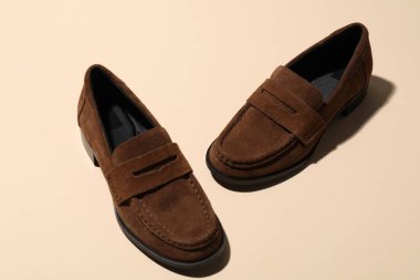 Pair of stylish brown shoes on beige background, closeup