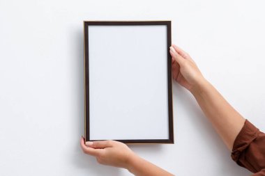 Beyaz duvara boş bir diploma çerçevesi asan kadın, yakın plan. Tasarım için model