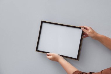 Işık duvarına boş bir diploma çerçevesi asan kadın, yakın plan. Tasarım için model