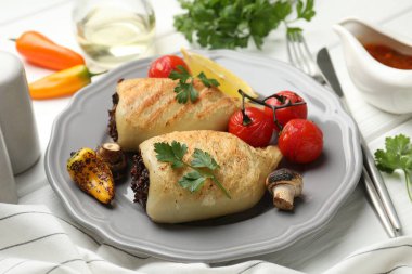 Mantar, maydanoz ve domatesle doldurulmuş leziz ızgara kalamar parçaları beyaz ahşap masada, yakın plan.