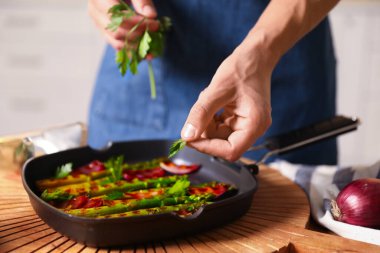 Maydanoz ve ızgara sebze ekleyen bir adam.