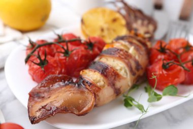 Lezzetli doldurulmuş mürekkep balığı, mikroyeşiller ve domatesler beyaz mermer masada, yakın plan.