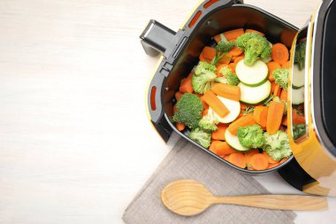 Beyaz ahşap masada çiğ havuç, brokoli ve kabak kızartma makinesi, üst manzara. Metin için boşluk