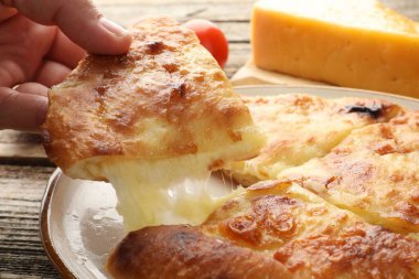 Ahşap masada nefis bir parça Megrelian Khachapuri alan kadın, yakın plan.