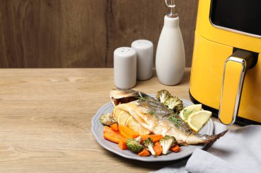 Pişmiş balık, biberiye, limon, sebzeler ve ahşap masa üzerinde tava, yakın plan. Metin için boşluk