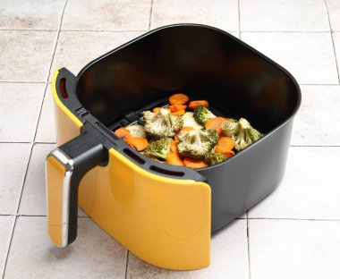 Pişmiş havuç, brokoli ve kabak. Beyaz fayanslı masada tava sepeti, yakın plan.