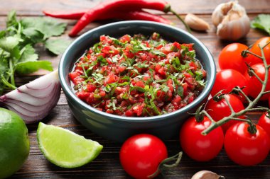 Tasty salsa sauce and ingredients on wooden table, closeup