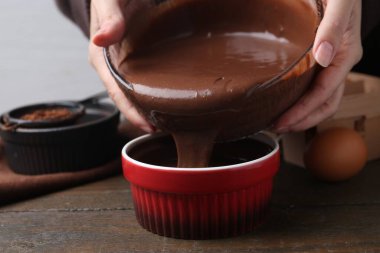 Ahşap masada çiğ çikolata hamurunu pişiren kadın, yakın plan.