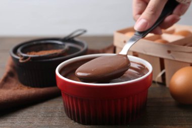 Tahta masadaki kasede çiğ çikolata hamuru olan kadın, yakın plan.