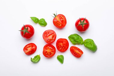 Beyaz arka planda taze kırmızı domates ve fesleğen yaprakları.