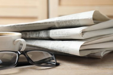 Gazete yığını, kahve ve bardaklar ahşap masada, yakın plan.