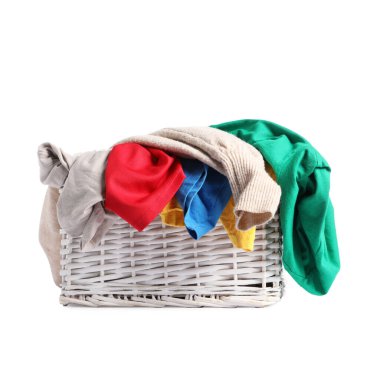 Hasır çamaşır sepeti beyaza izole edilmiş renkli kıyafetlerle dolu.