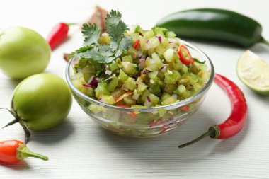 Lezzetli salsa sosu ve malzemeler beyaz ahşap masada, yakın plan.