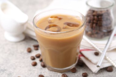 Tasty iced coffee with milk and beans on light table, closeup